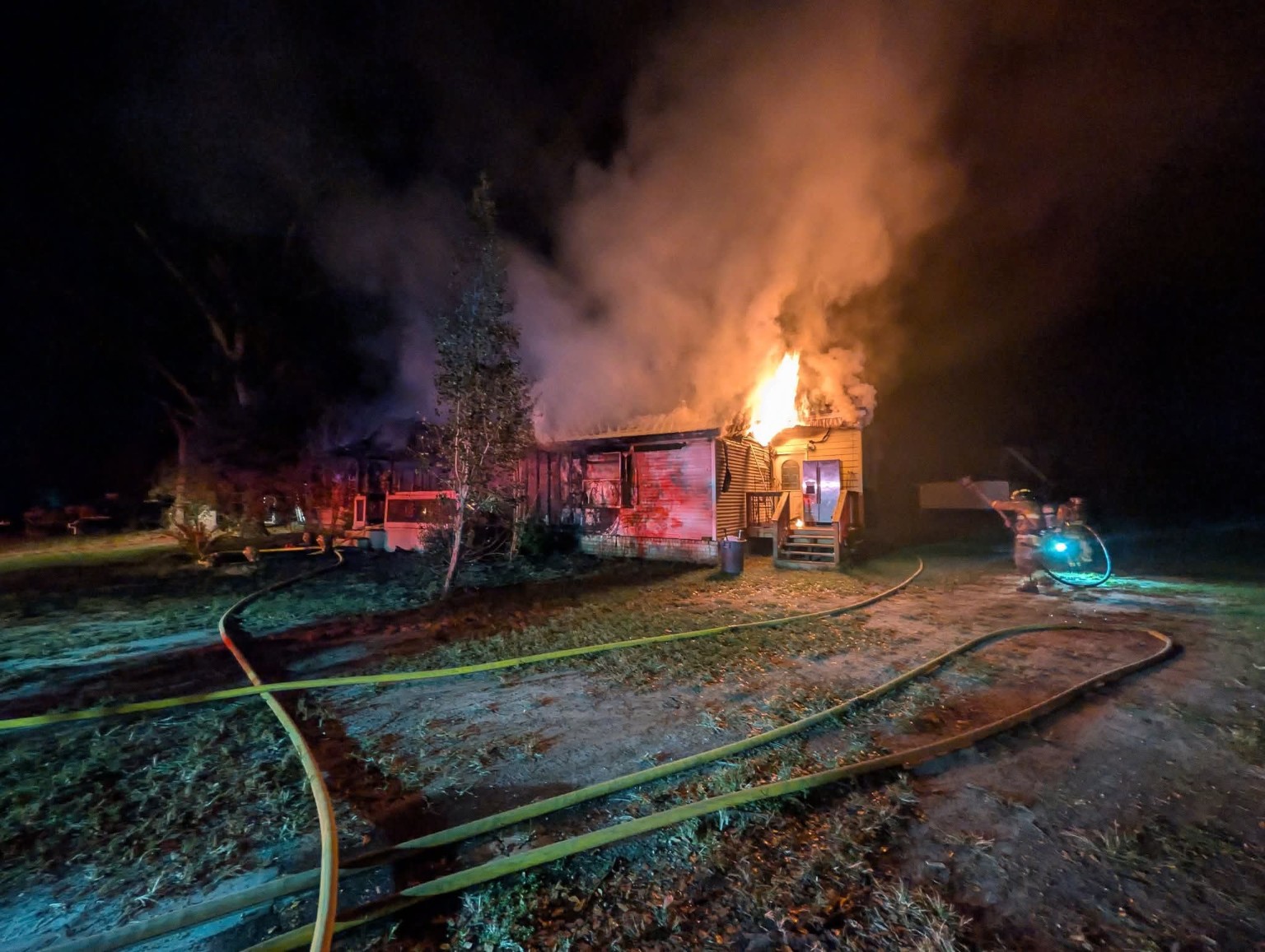 Flames and smoke rise from a Long County home as firefighters work at the scene at night.