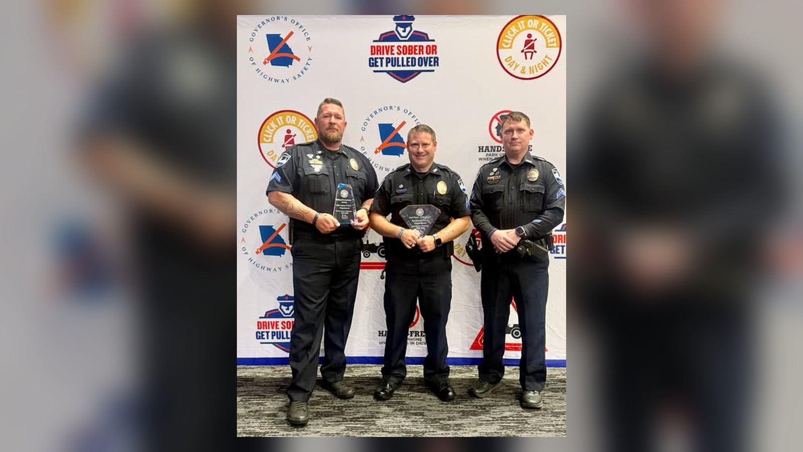 Three Savannah police officers pose holding awards at the 2026 Georgia Governor’s Challenge Awards, in front of a Georgia Governor’s Office of Highway Safety backdrop.