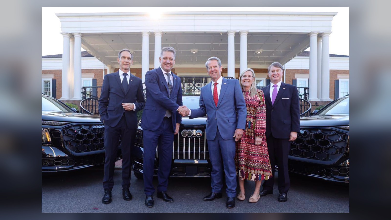 Georgia Gov. Brian Kemp and Audi officials pose in front of Audi vehicles after announcing the company's planned U.S. manufacturing plant in Peach County.